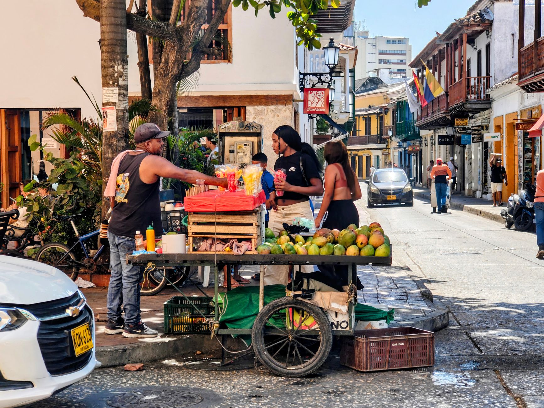 A Palenquera fruit vendor in traditional dress sells mango and papaya near Plaza de la Aduana in the Walled City.