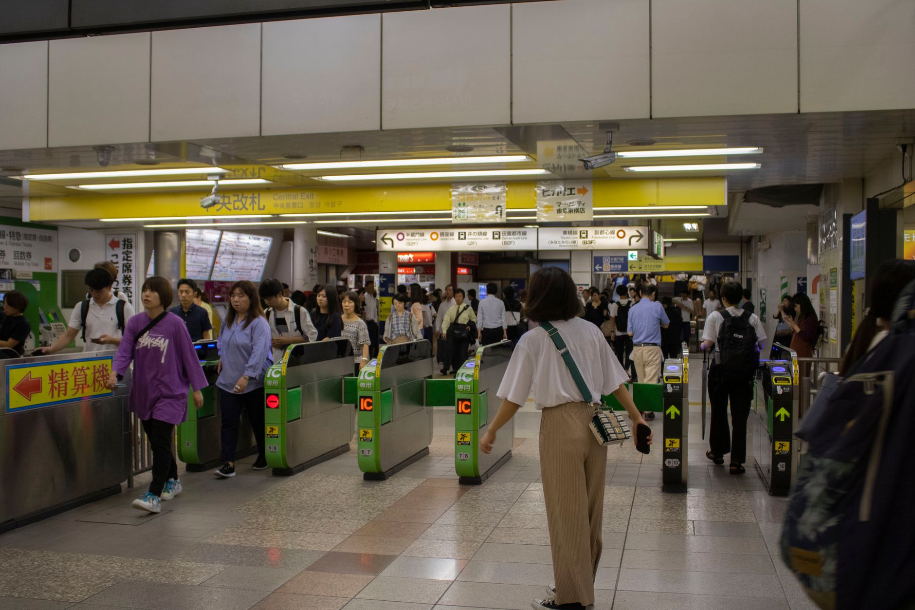 A traveler tapping a Suica IC card at a ticket gate in a Tokyo train station