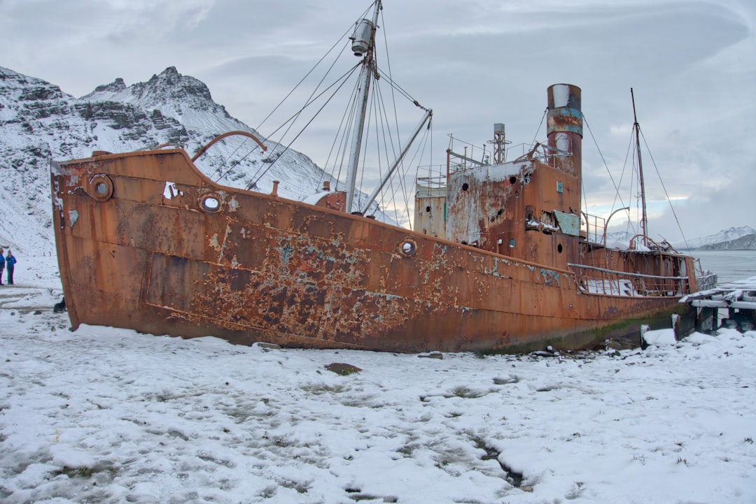 Abandoned whaling station buildings and tanks at Grytviken, South Georgia, with snow-capped mountains behind