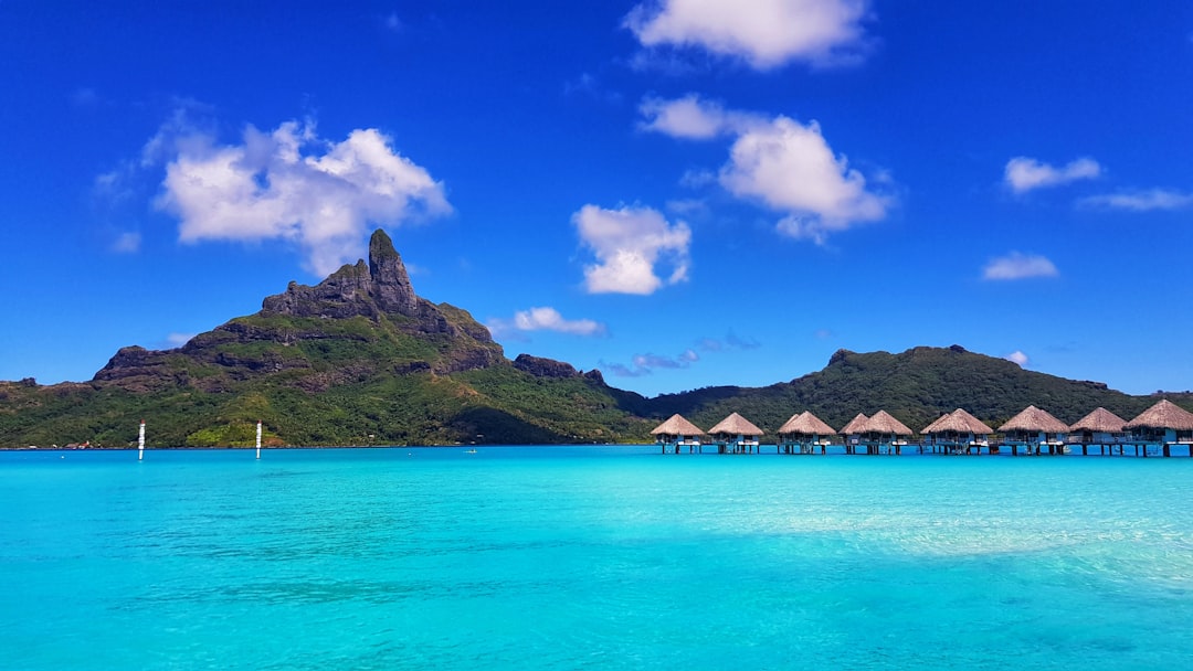Aerial view of overwater villas on stilts in the turquoise lagoon of Bora Bora with Mount Otemanu in the background