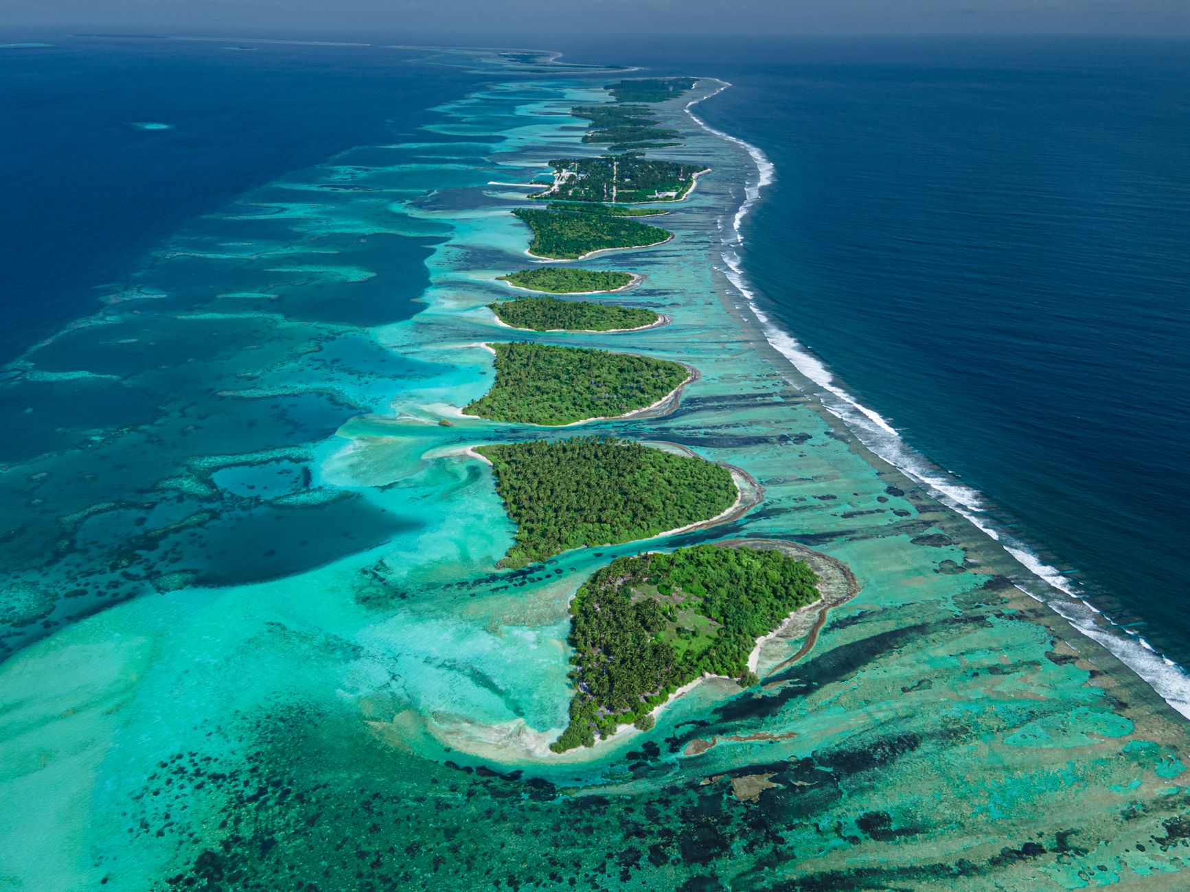 Aerial view of the turquoise lagoon and coral patches surrounding Taha'a island
