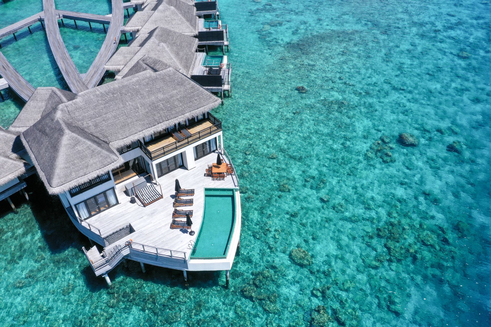 An overwater spa pavilion with a glass floor revealing the reef below.