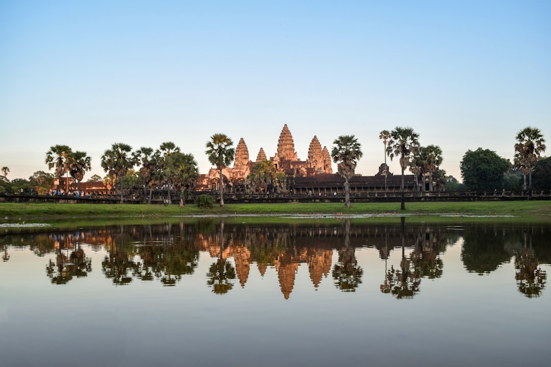 Angkor Wat's five towers reflected in the moat, seen from the causeway at sunrise.