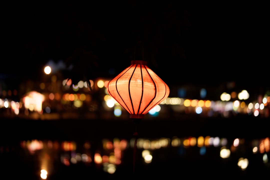 Colorful silk lanterns strung above a riverside street in Hoi An at dusk