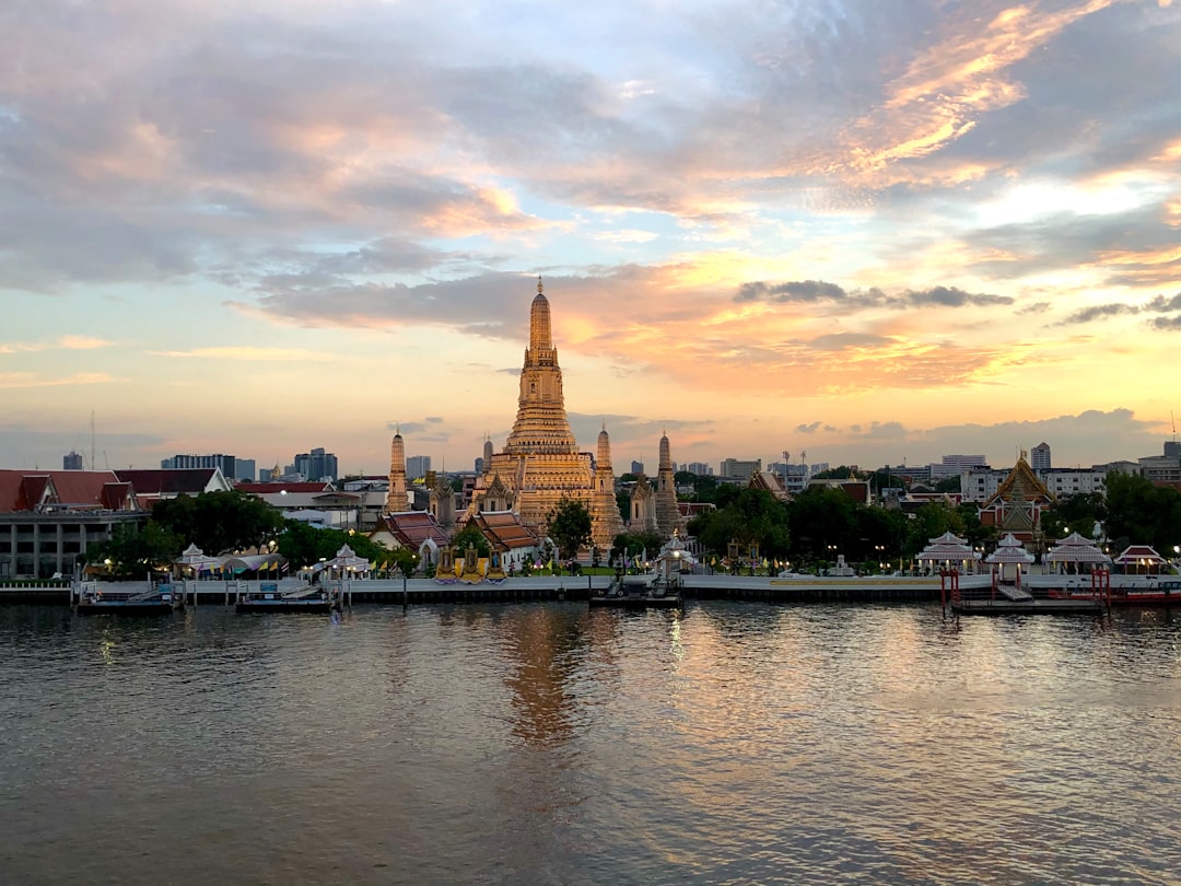 Dawn light on the Chao Phraya River with traditional temple and boats in Bangkok