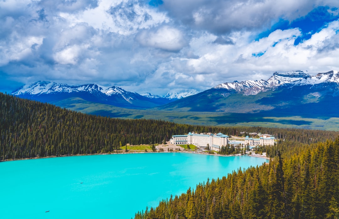 Fairmont Chateau Lake Louise beside the turquoise waters of Lake Louise with snow-capped peaks behind