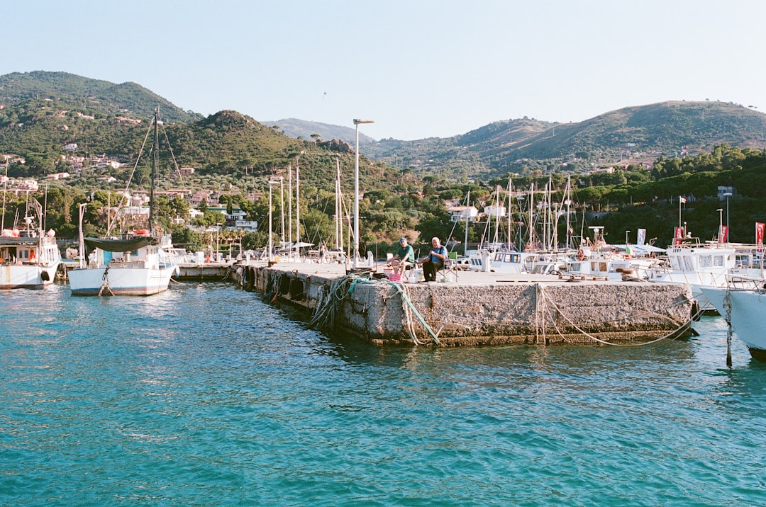 Fishermen repair nets and maintain boats in working harbors, visible primarily when summer tourism traffic subsides.