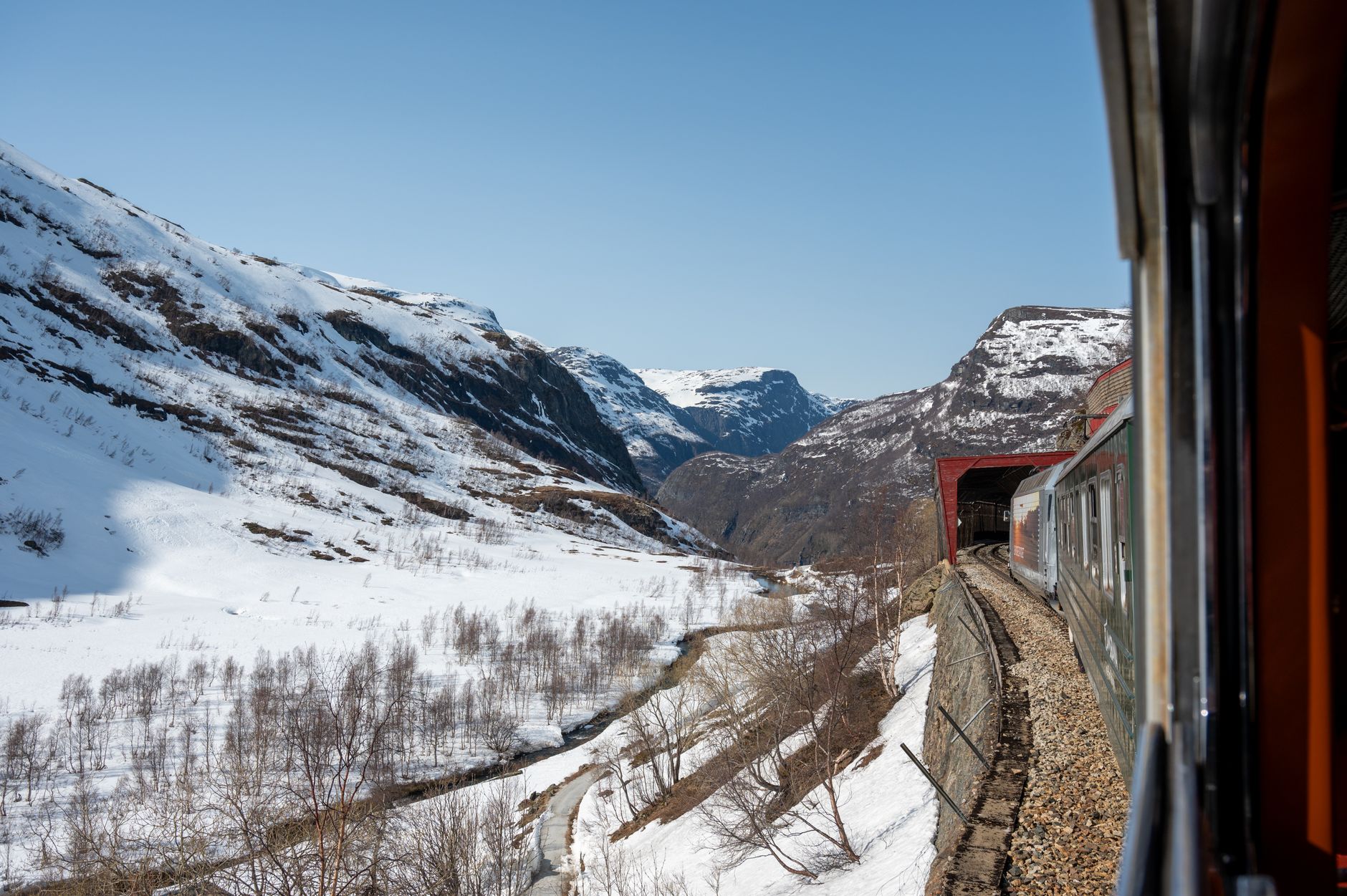 Flåm Railway train winding down a steep green fjord valley in Norway
