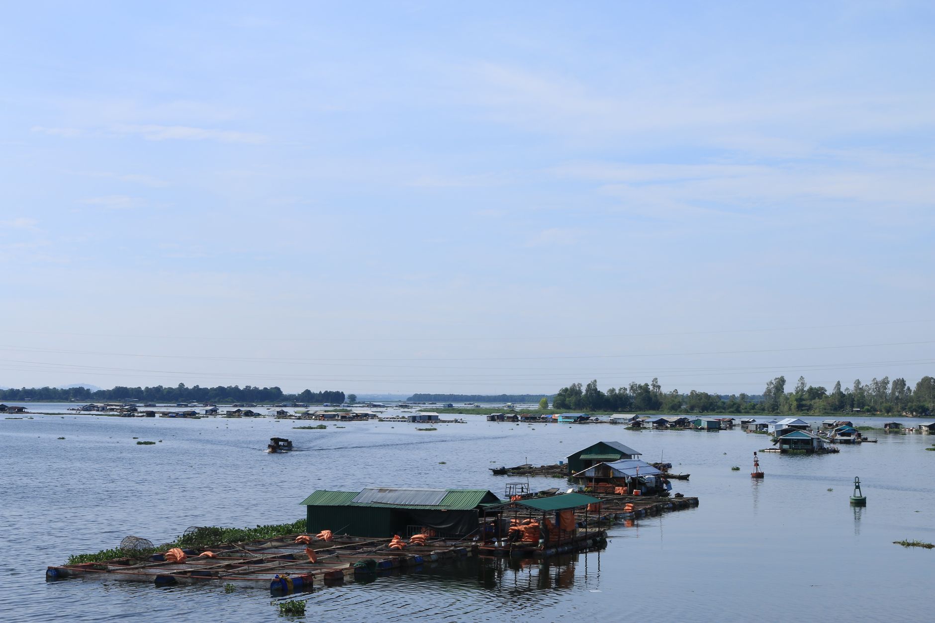 Floating fish pens tethered beneath stilt houses near Chau Doc, Vietnam.