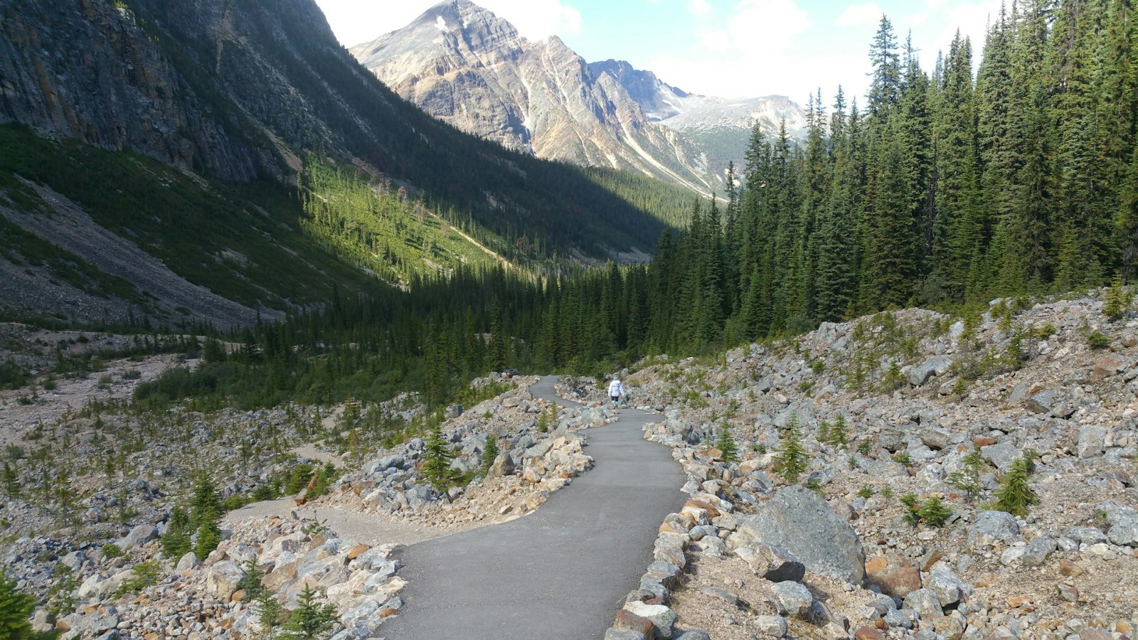 Narrow mountain road with sharp switchback curves climbing toward alpine peaks