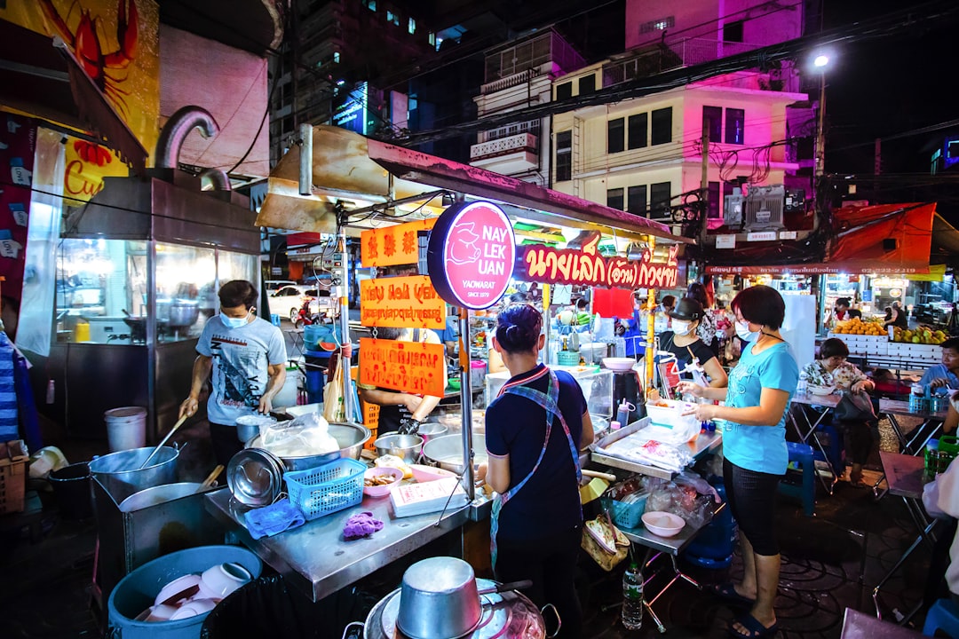 Night market street food scene in Bangkok's Chinatown with vendors and diners