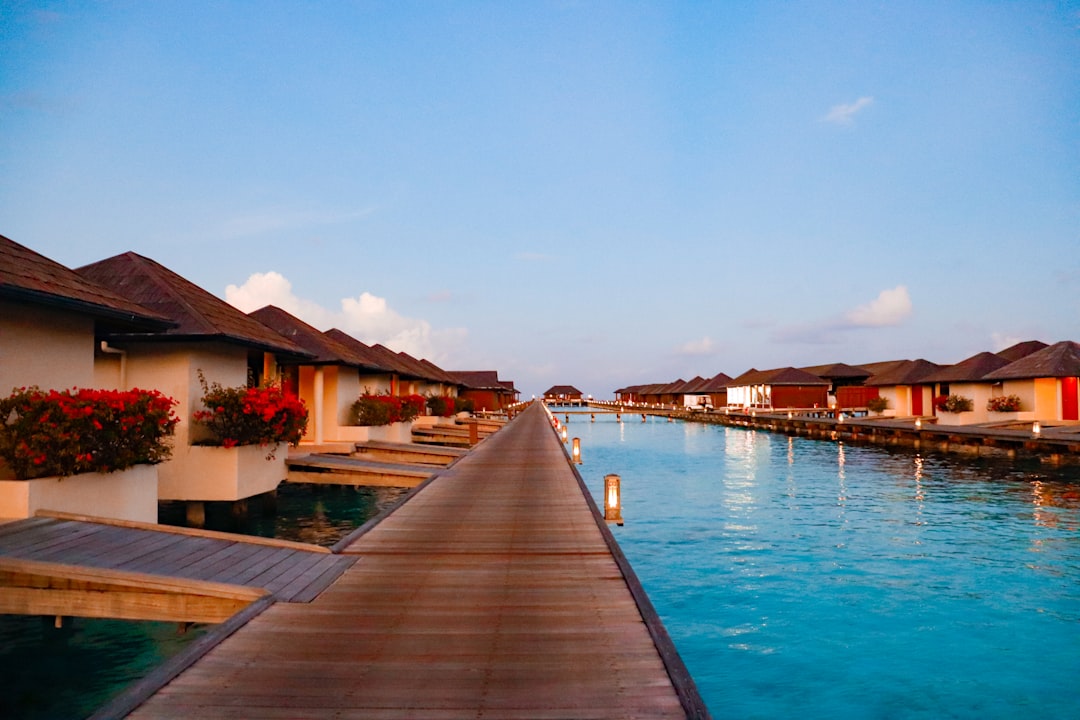 Overwater villa deck looking out over a pale turquoise Maldivian lagoon at sunrise