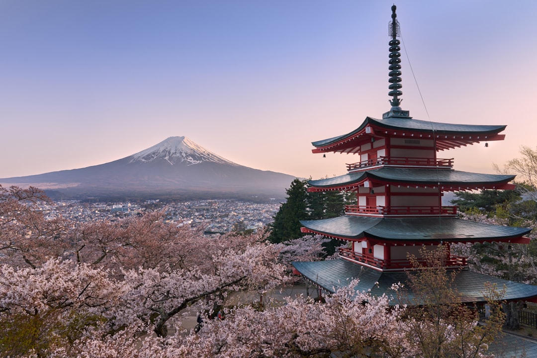 Red pagoda with cherry blossom trees and Mount Fuji in the background