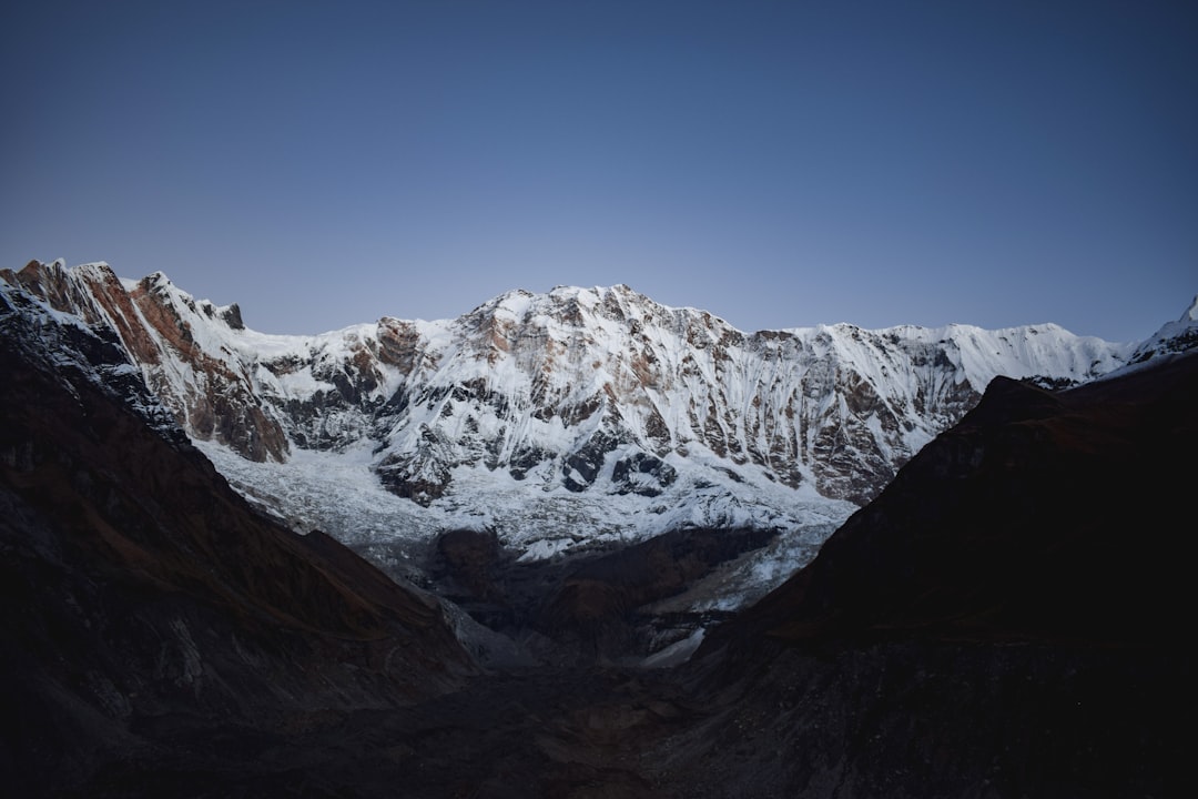 Snow-covered mountain pass with distant peaks under clear sky