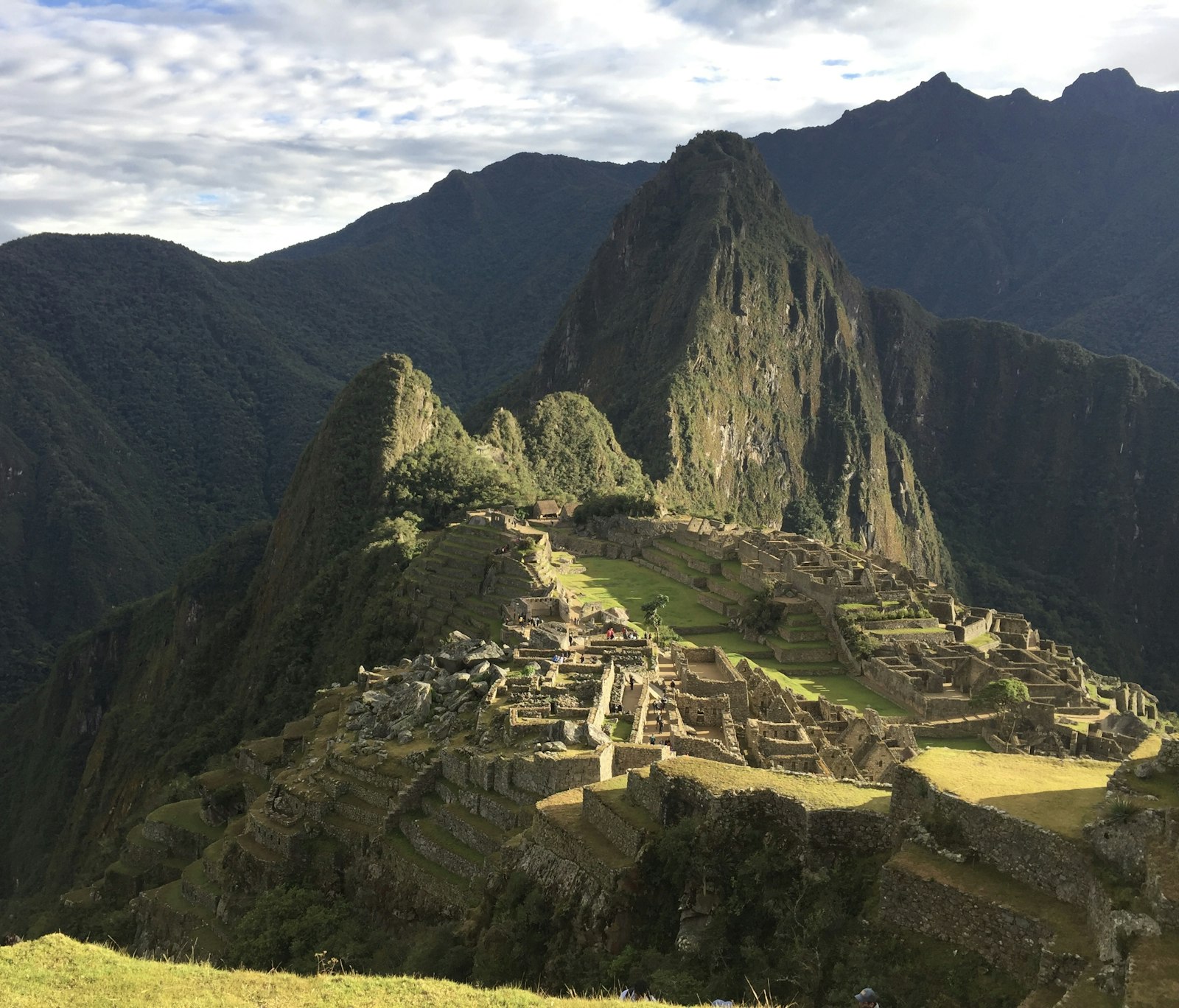 Terraced stone citadel of Machu Picchu wreathed in morning mist with Huayna Picchu peak behind it