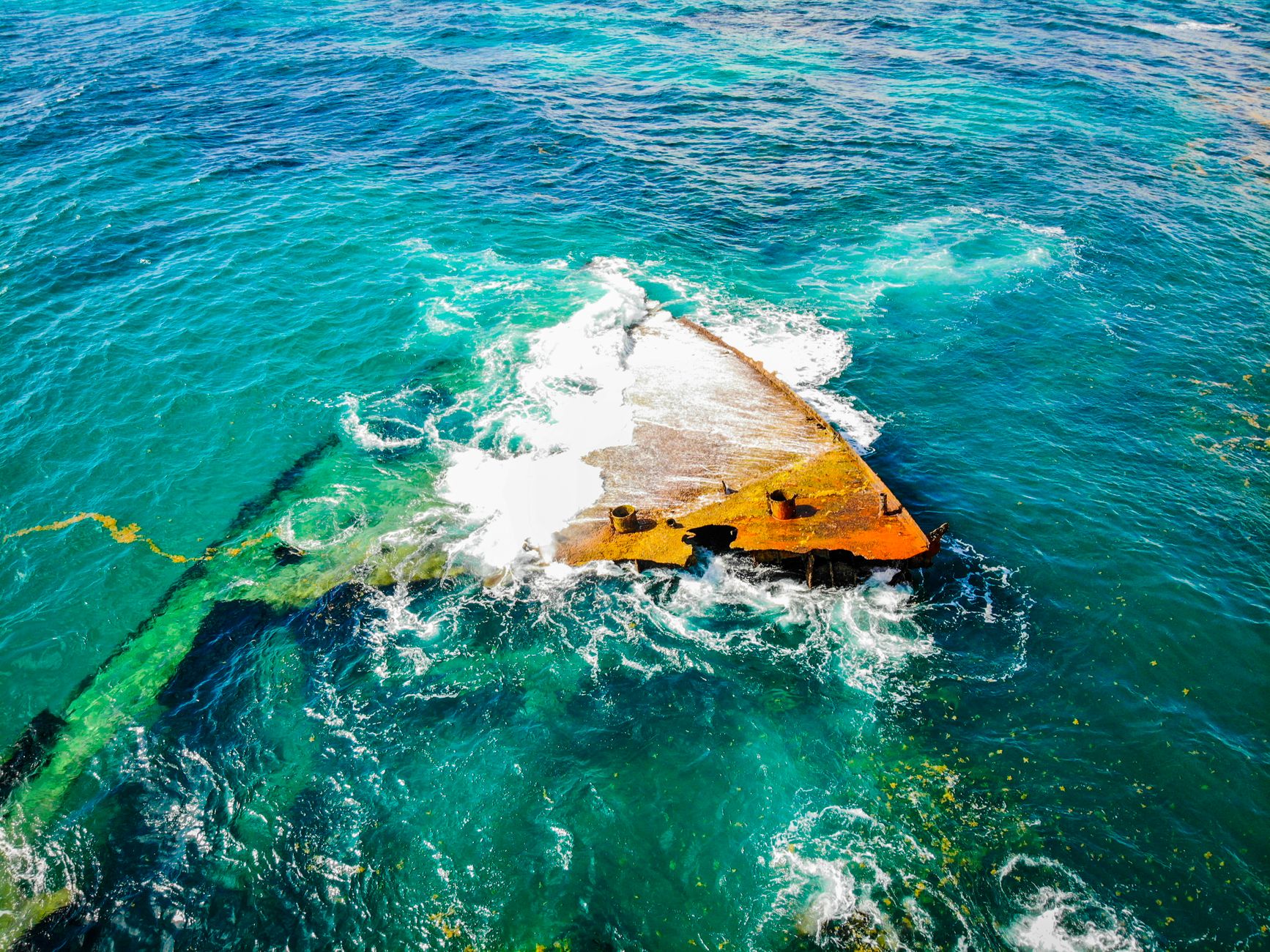 The exposed hull of the Kinugawa Maru, visible above the waterline at low tide off Bonegi Beach.