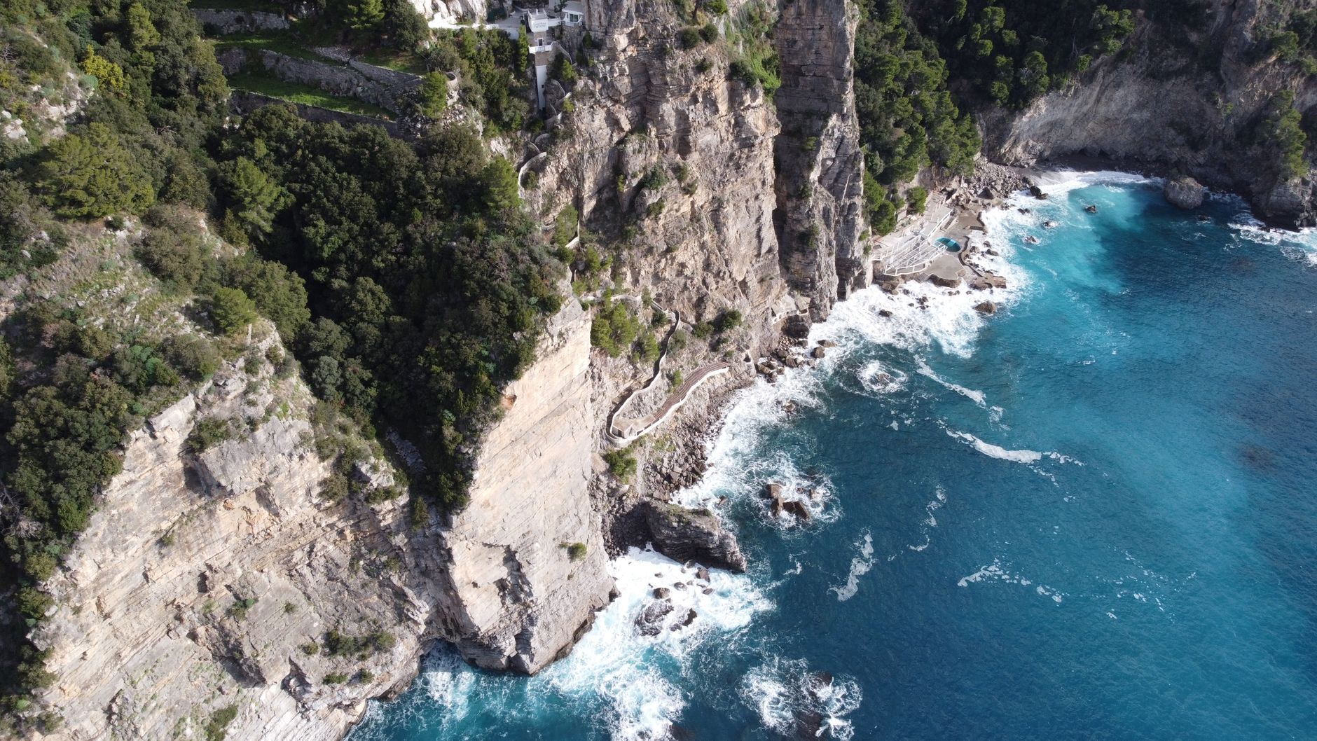 The Path of the Gods trail traces the cliffs between Bomerano and Nocelle, with Capri visible on a clear day.