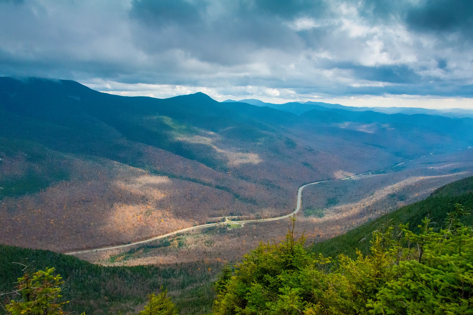 The Swift River flows alongside Route 112, framing the foliage in reflective water and creating natural depth in the landscape.