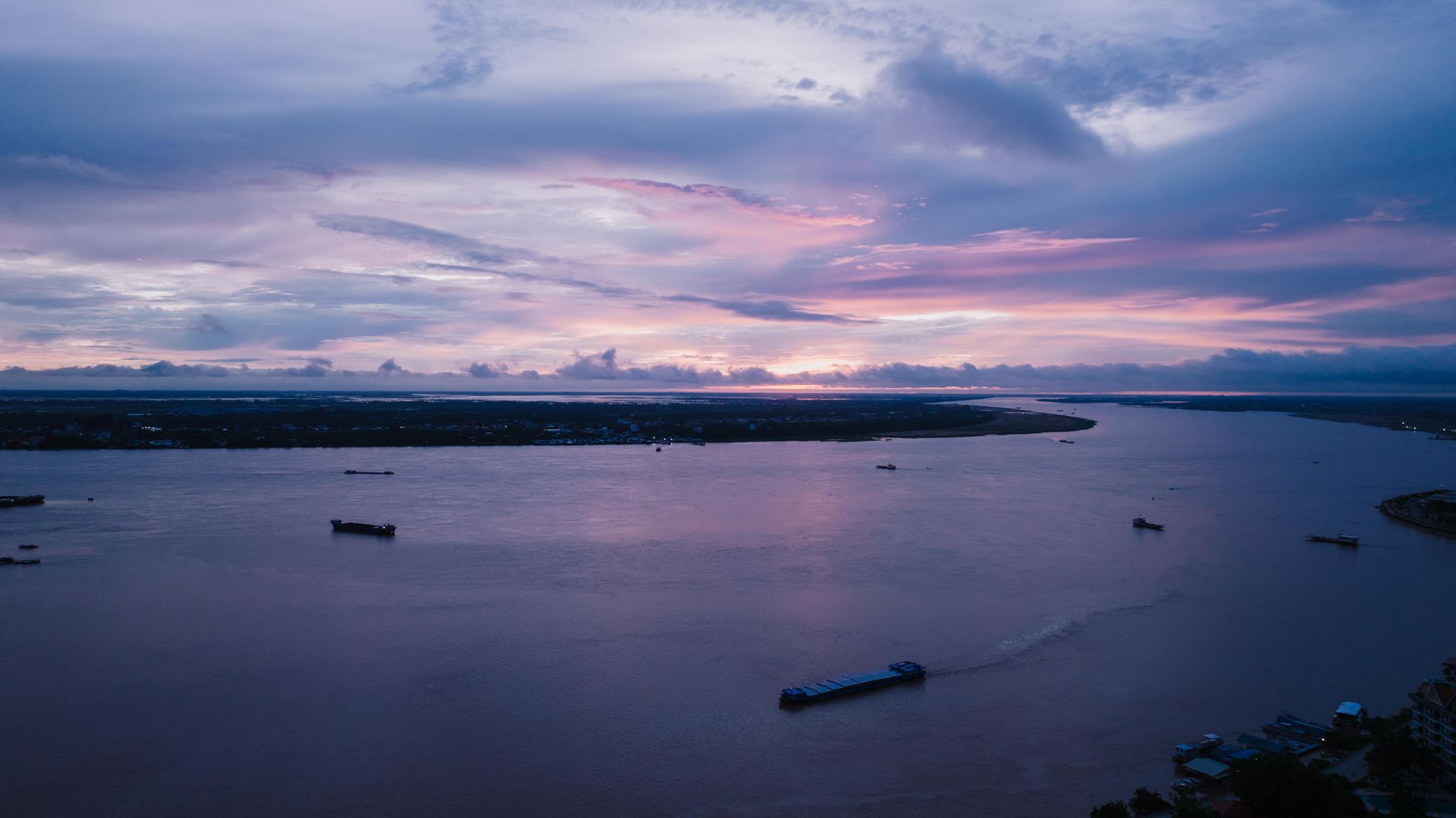 Traditional wooden boats on the lower Mekong River at sunset near the Cambodia-Vietnam border