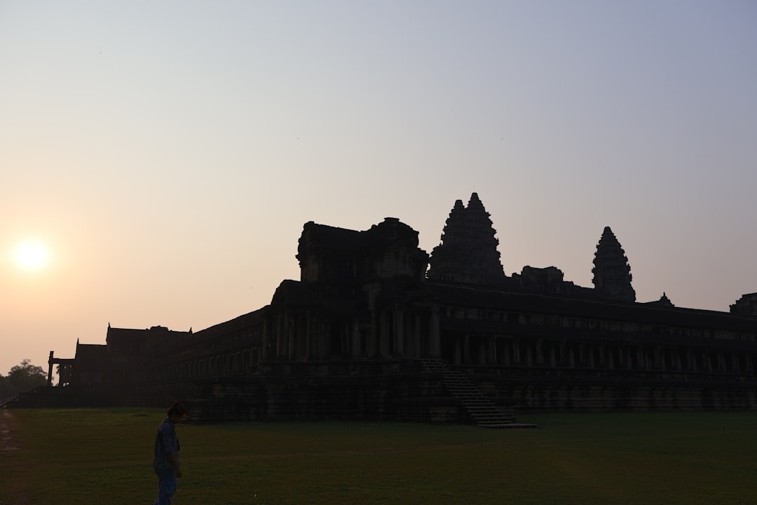 Visitors walking the stone causeway toward Angkor Wat at sunrise
