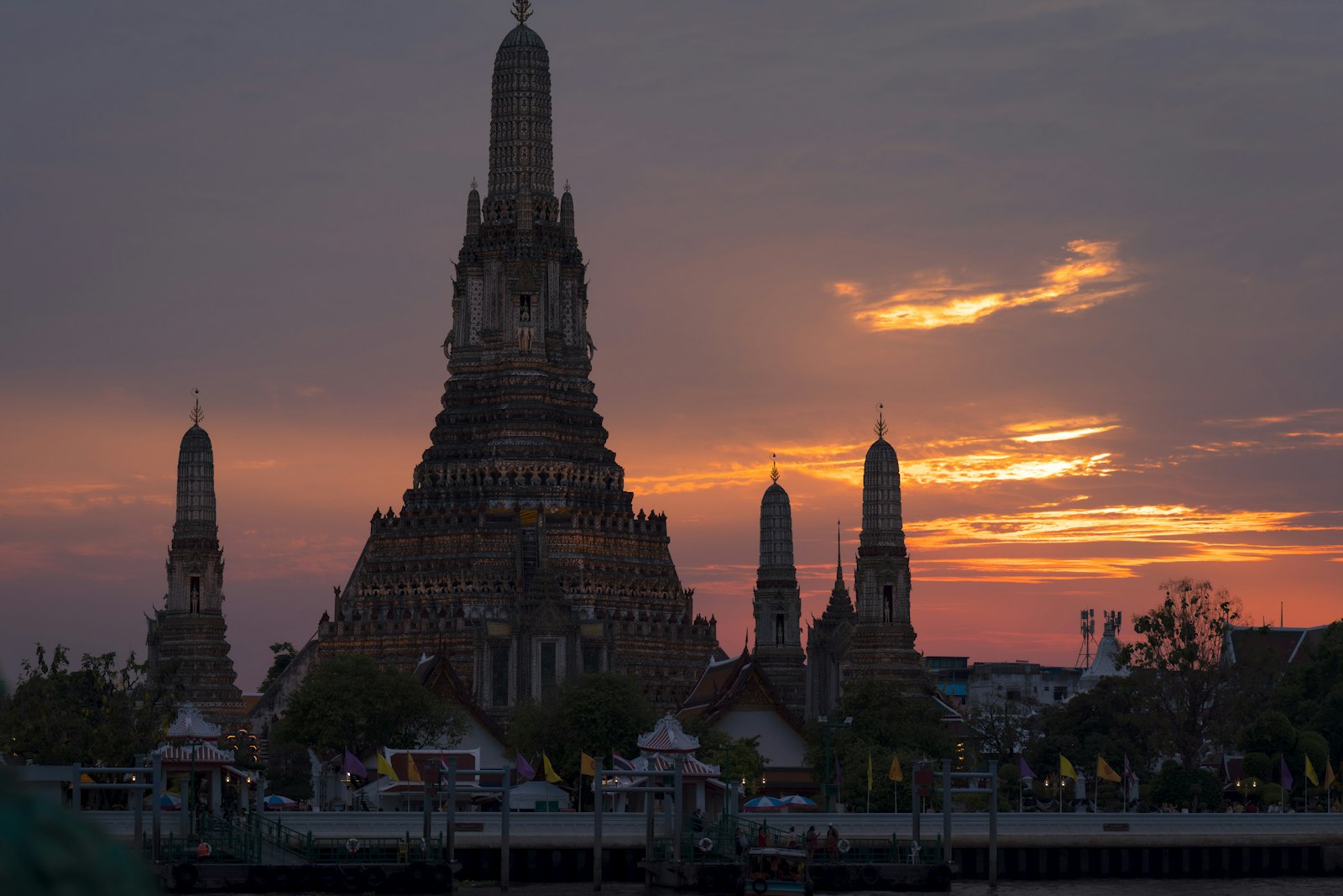 Wat Arun temple glowing at sunset beside the Chao Phraya River in Bangkok