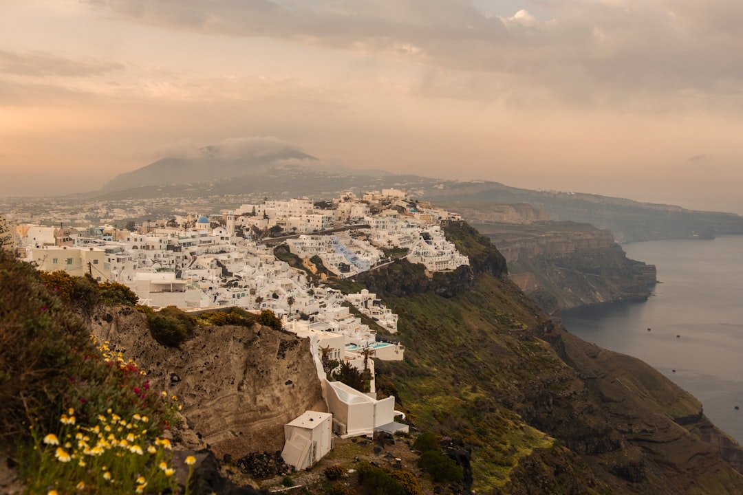 Whitewashed buildings perched on Santorini's cliff edge overlooking the caldera at golden hour
